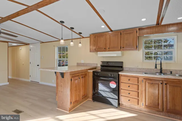 a kitchen with stainless steel appliances granite countertop a stove a sink and a refrigerator with wooden cabinets