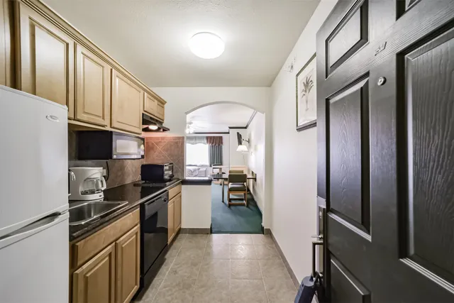 a kitchen with stainless steel appliances granite countertop a refrigerator a sink dishwasher a stove and white countertops with wooden floor