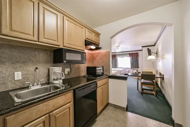 a kitchen with granite countertop a sink dishwasher stove and cabinets
