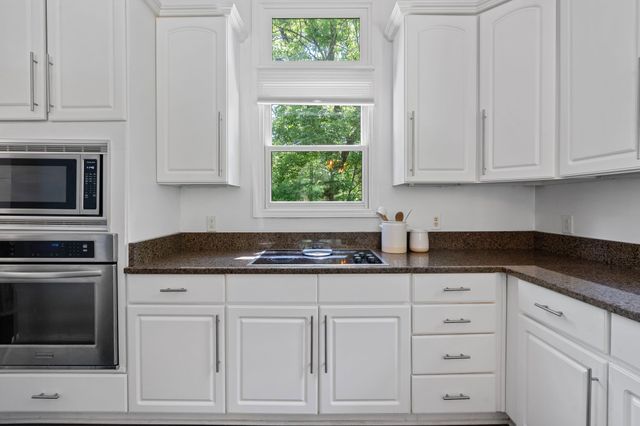 a kitchen with granite countertop white cabinets and window
