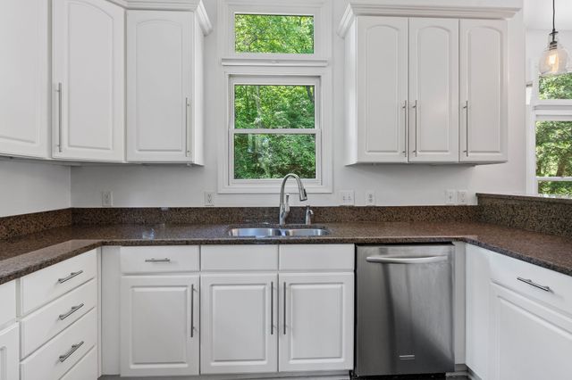 a kitchen with white cabinets and a window