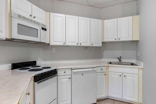 a kitchen with white cabinets and black appliances