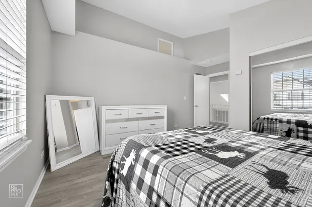 a bedroom with a bed next to a window with wooden floor