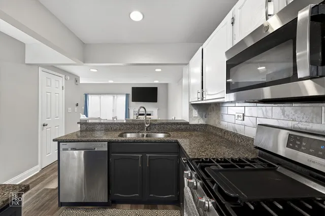 a kitchen with kitchen island granite countertop a sink and a stove