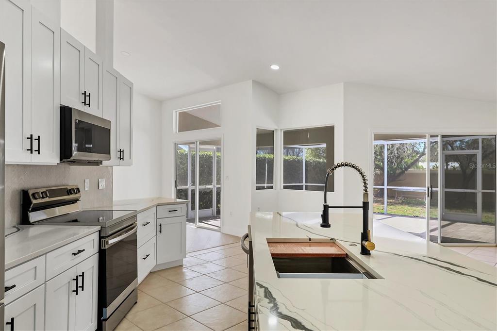 6409 Stone River Road Bradenton, FL 34203 - Photo 13 of 55 a kitchen with kitchen island a sink a stove and white cabinets
