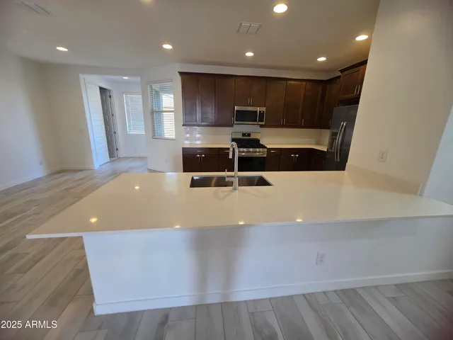 a large white kitchen with wooden floors and stainless steel appliances