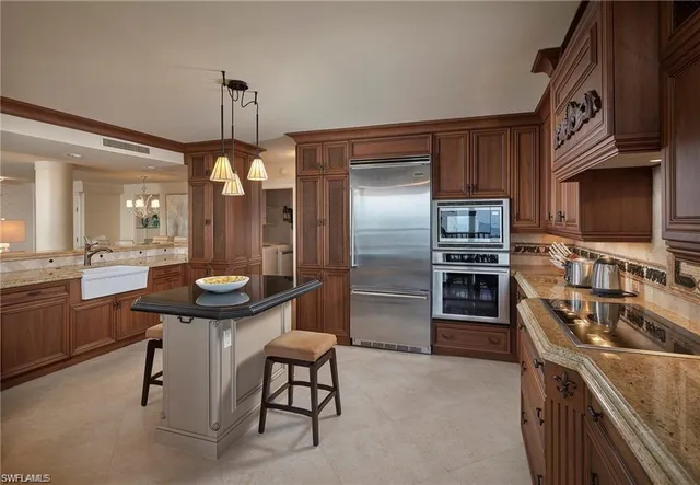 a kitchen with stainless steel appliances a sink a stove a refrigerator cabinets and a dining table