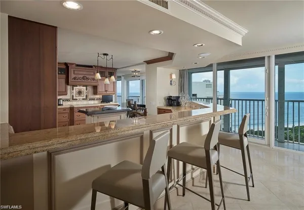 a kitchen with stainless steel appliances kitchen island granite countertop a table chairs and a refrigerator