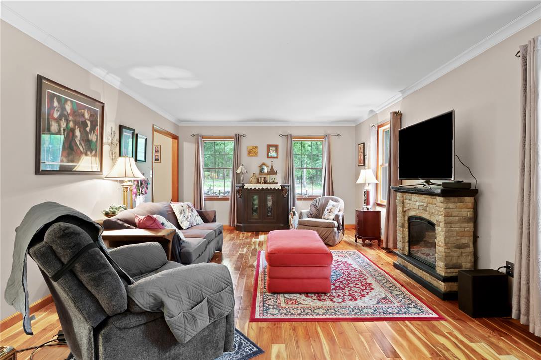209 Remington Road East Stroudsburg, PA 18301 - Photo 7 of 41 Hardwood floors and crown molding elevate this spacious living area with a cozy stone fireplace.