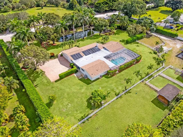 a view of a house with a big yard and palm trees