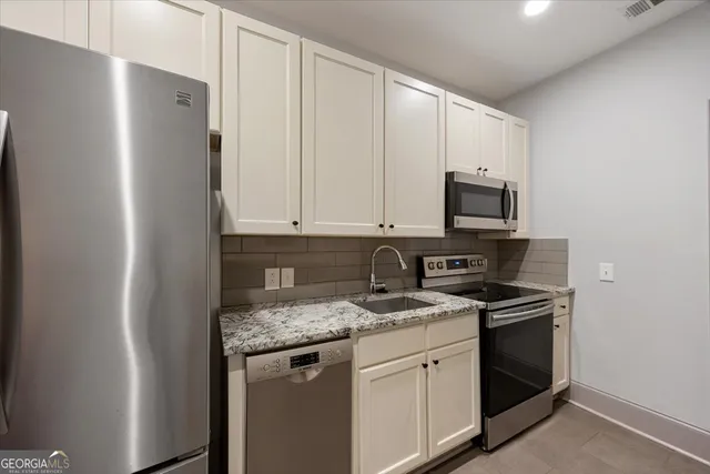 a kitchen with stainless steel appliances granite countertop white cabinets stove a microwave and a refrigerator