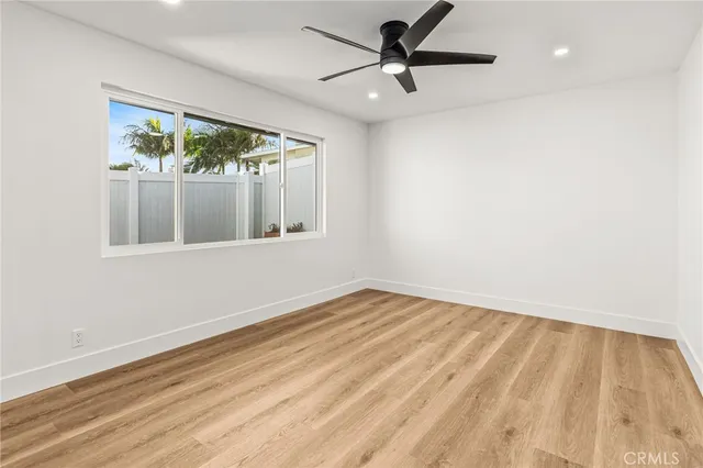a view of empty room with wooden floor and fan
