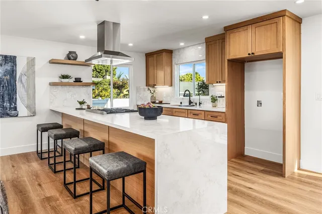 a room with stainless steel appliances kitchen island granite countertop dining table chairs and a refrigerator