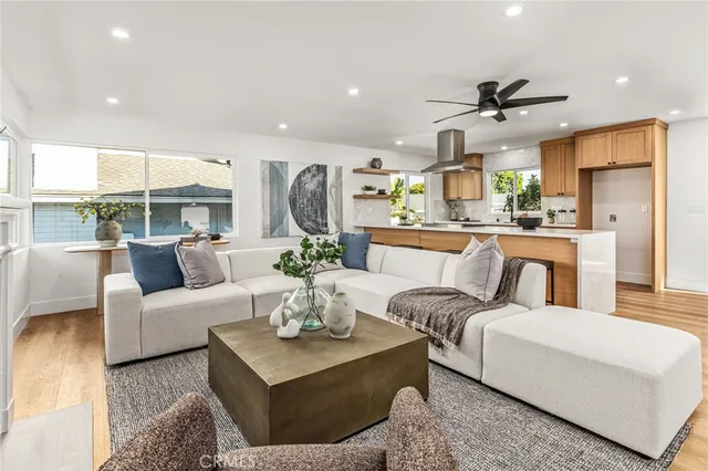 a living room with furniture kitchen view and a wooden floor
