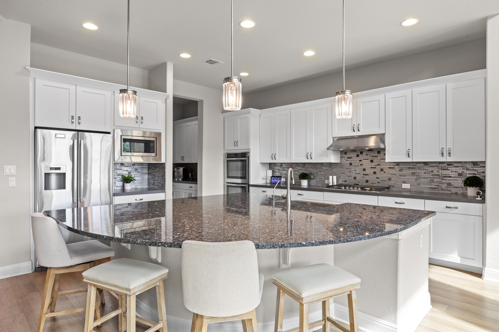 15705 Colinas Cove Bee Cave, TX 78738 - Photo 14 of 40 Kitchen featuring light wood-style floors, dark stone countertops, and backsplash