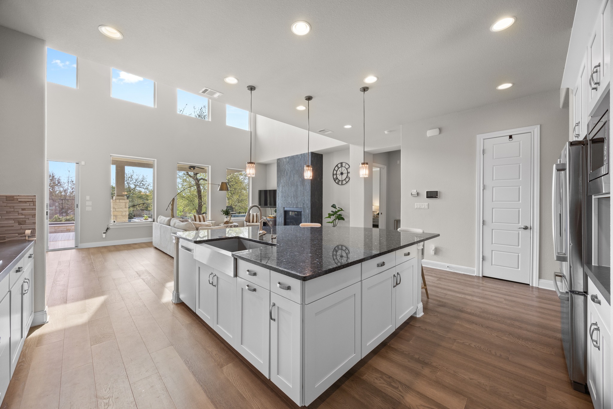 15705 Colinas Cove Bee Cave, TX 78738 - Photo 16 of 40 Kitchen featuring white cabinetry, a kitchen island with sink, dark wood finished floors, and a high ceiling