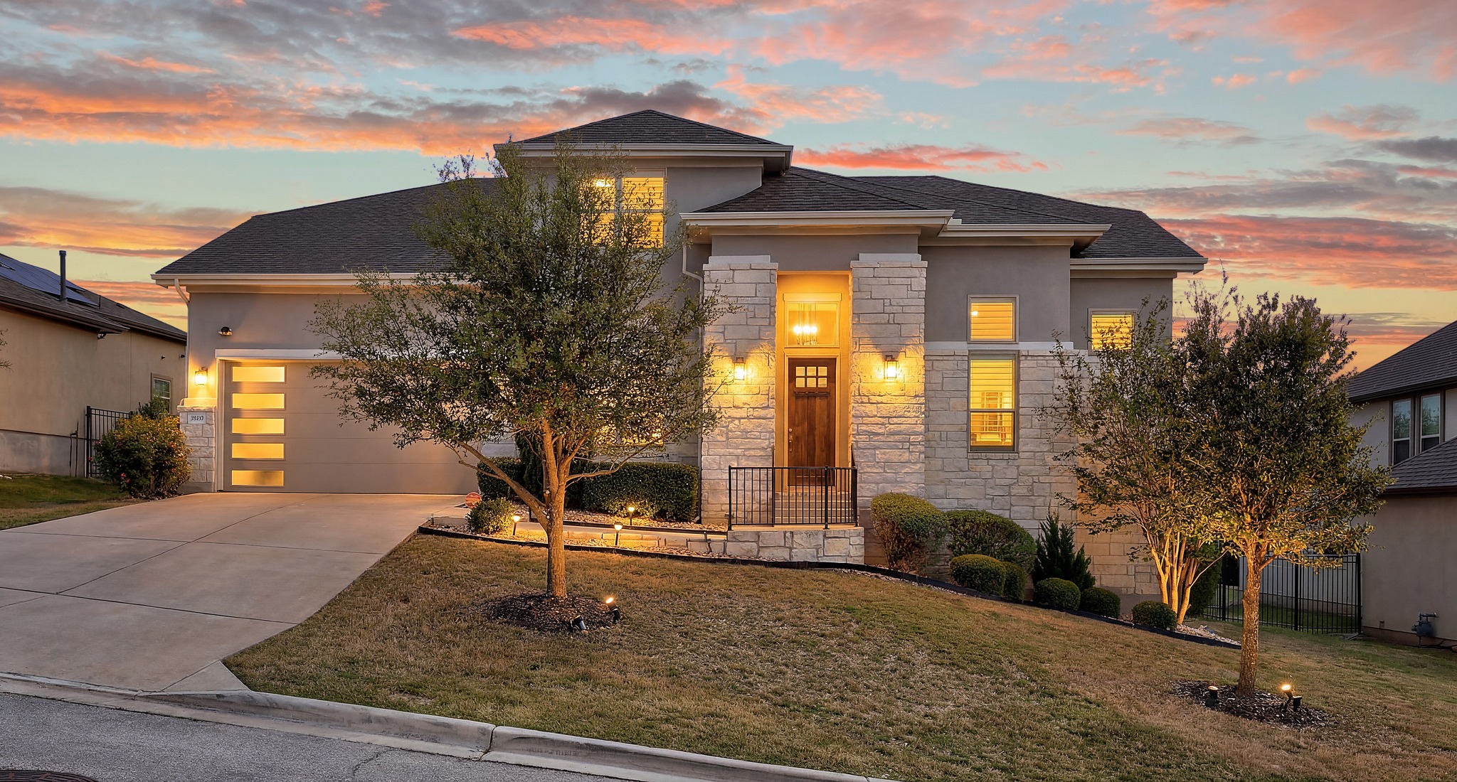 15705 Colinas Cove Bee Cave, TX 78738 - Photo 2 of 40 View of front facade with an attached garage, stone siding, concrete driveway, a yard, and stucco siding
