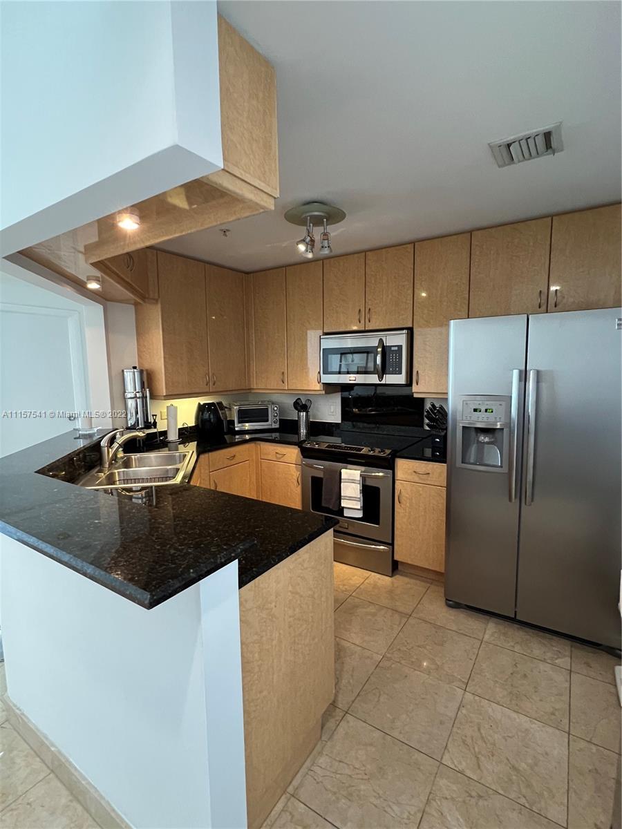 801 Brickell Key Boulevard, Unit 1506 Miami, FL 33131 - Photo 10 of 27 a kitchen with granite countertop a sink a counter top space stainless steel appliances and cabinets