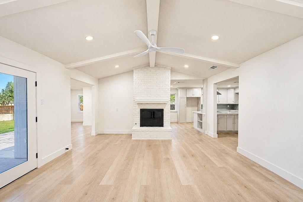 1904 Apollo Road Richardson, TX 75081 - Photo 4 of 40 Vaulted ceiling with exposed beams, recessed lighting, wood-finish flooring, white brick fireplace, and modern ceiling fan