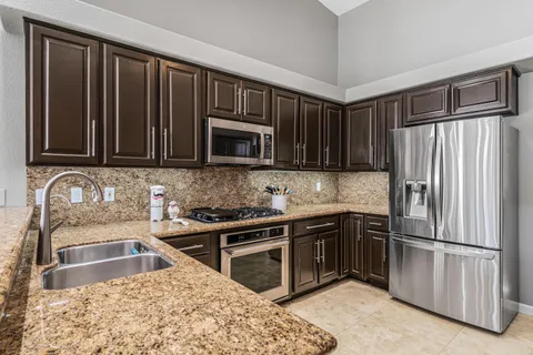 a kitchen with granite countertop a refrigerator stove and microwave