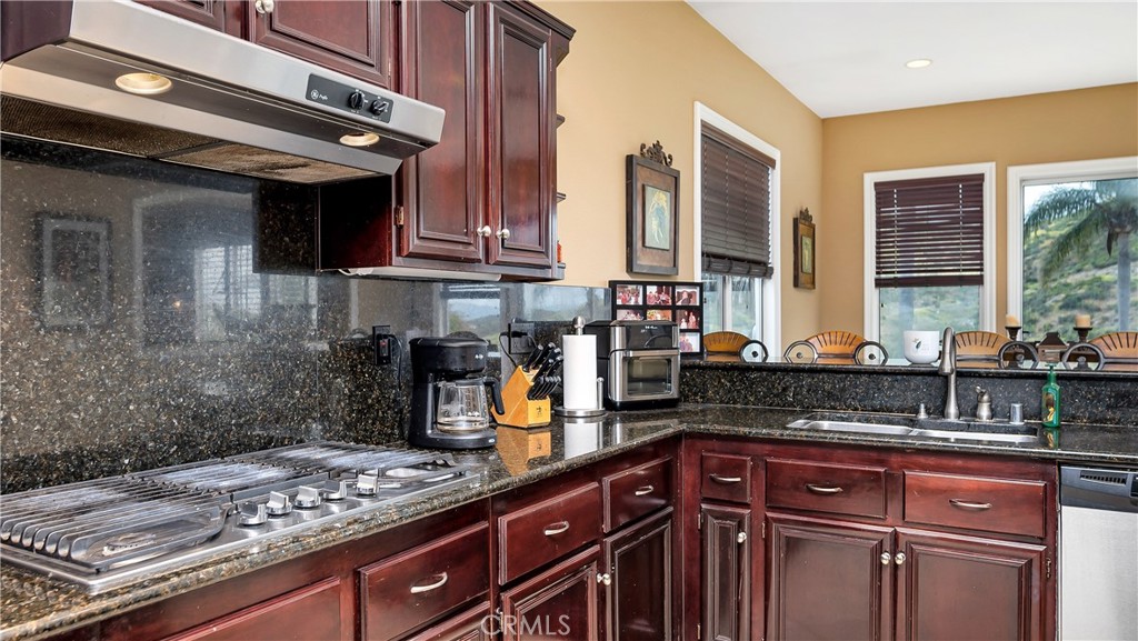 23894 Trail Duster Court Perris, CA 92570 - Photo 22 of 75 a kitchen with stainless steel appliances granite countertop a sink a stove and a wooden cabinets