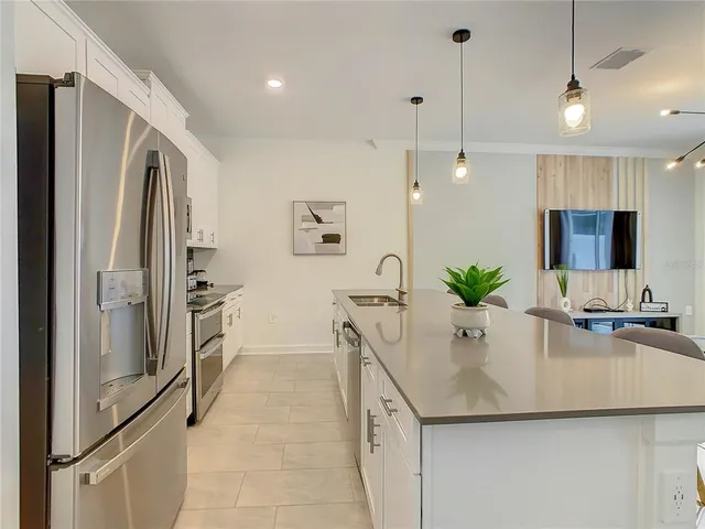 a kitchen with stainless steel appliances a sink a refrigerator a counter space and a refrigerator