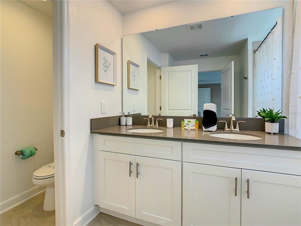 2573 Reading Trail Kissimmee, FL 34746 - Photo 36 of 54 a bathroom with a granite countertop sink a toilet and a mirror