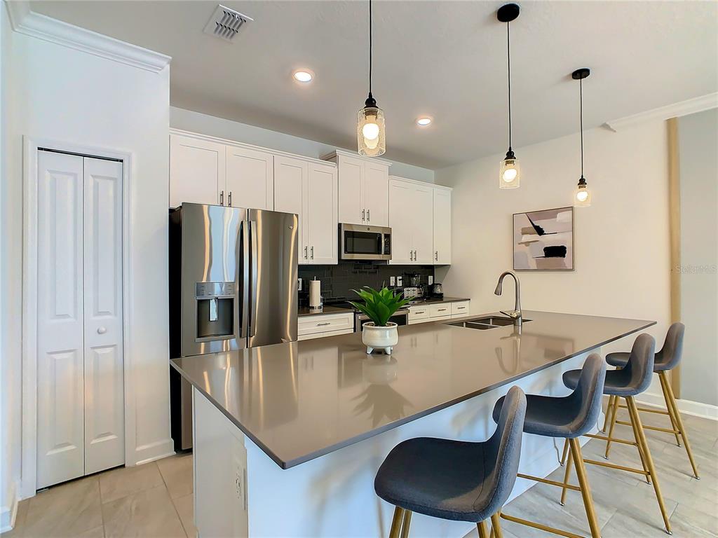 2573 Reading Trail Kissimmee, FL 34746 - Photo 10 of 54 a kitchen with stainless steel appliances granite countertop a sink a stove a refrigerator cabinets and chairs