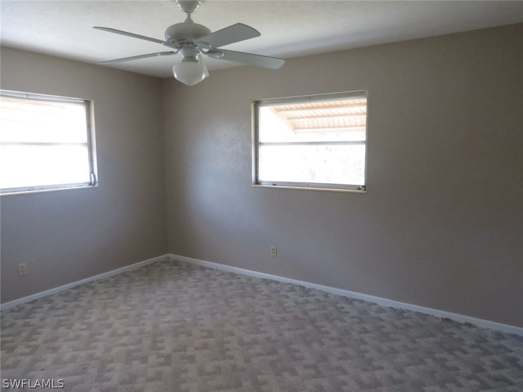 302 Penn Road West Lehigh Acres, FL 33936 - Photo 9 of 10 an empty room with a window and a fan