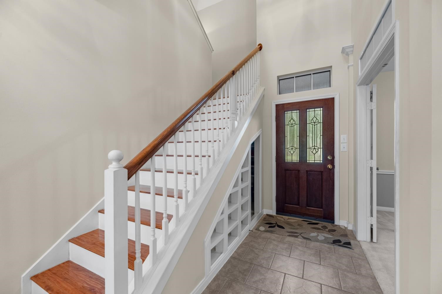 5724 Shady Hollow Court Rosharon, TX 77583 - Photo 5 of 27 Welcoming two-story entryway featuring soaring ceilings, tile flooring, and a beautiful wood-and-white staircase that creates a warm first impression. The seller added a custom shoe shelf for everyday convenience, along with extra storage tucked underneath the stairs—an ideal flex space with potential for pet storage, a cozy dog nook, or additional organization. Just off the front entry, the study offers a convenient space for a home office, sitting room, or formal flex area.
