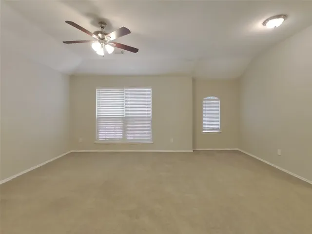 an empty room with chandelier fan and windows