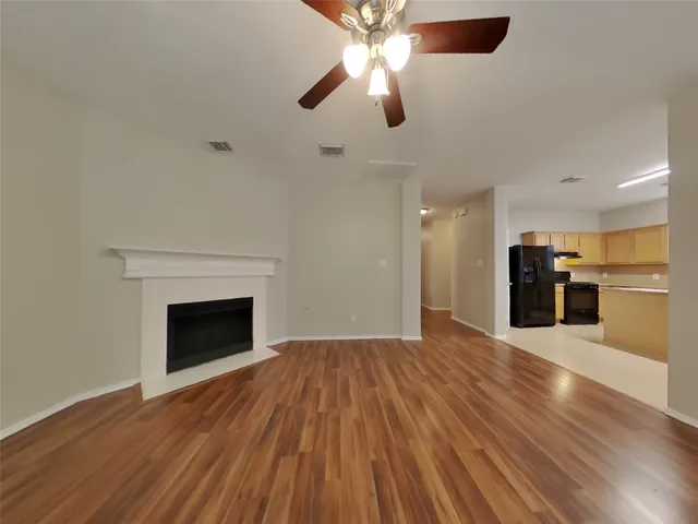 a view of an empty room with wooden floor fireplace and a window