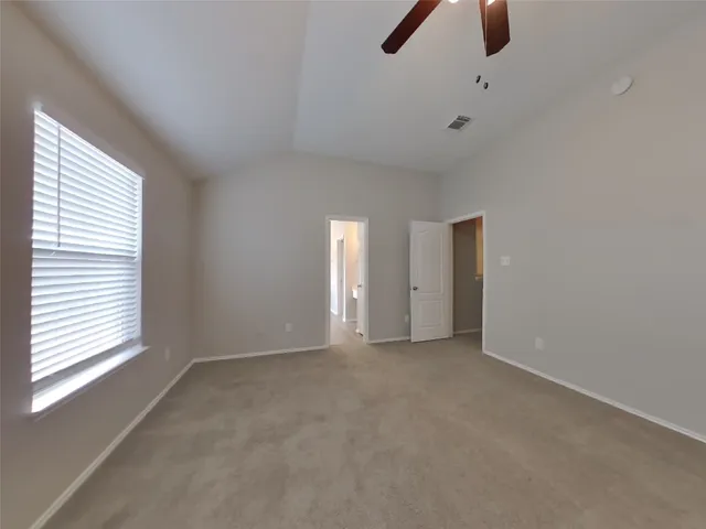 a view of an empty room with window and a ceiling fan