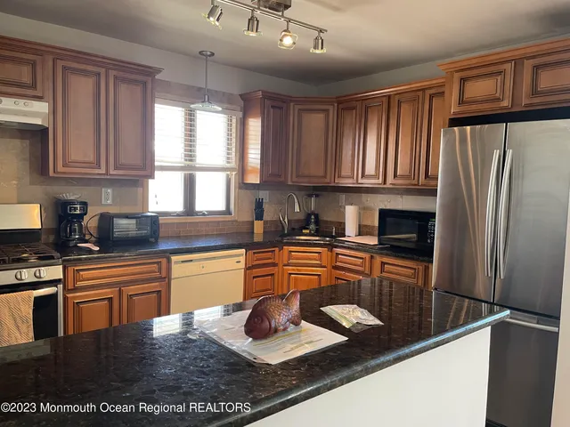 a kitchen with stainless steel appliances granite countertop a refrigerator sink stove microwave and cabinets