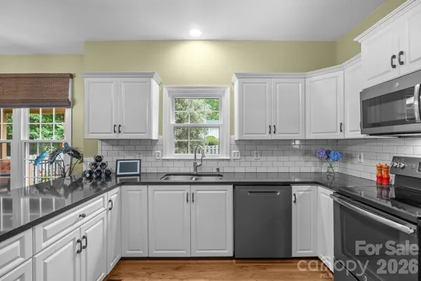 a kitchen with stainless steel appliances granite countertop a sink a stove and cabinets