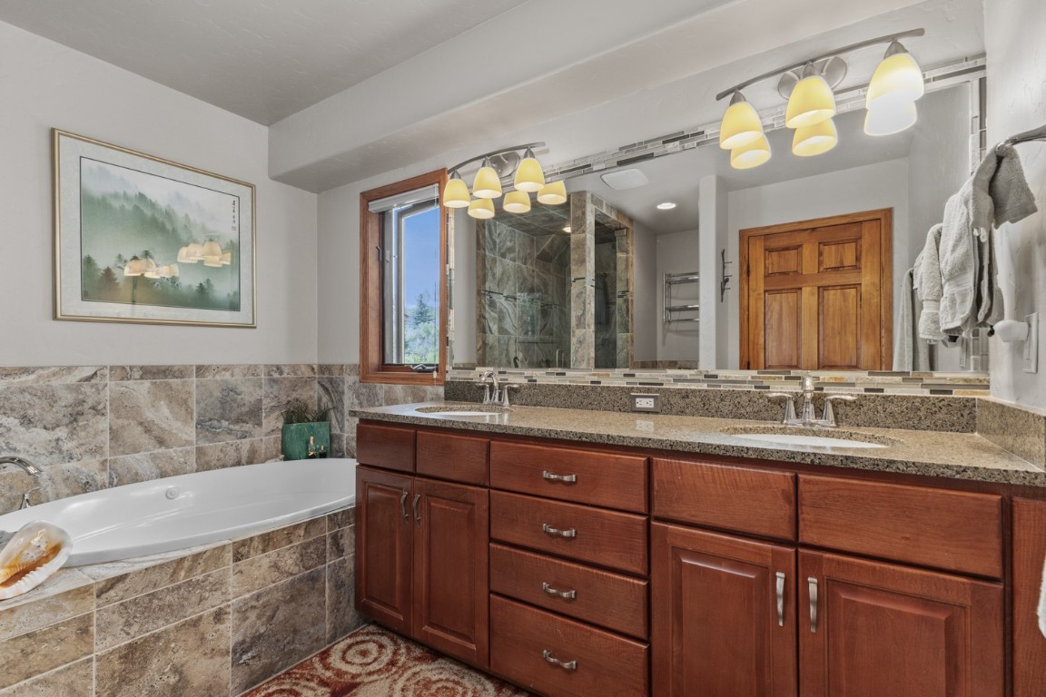 1215 Ridge View Drive Steamboat Springs, CO 80487 - Photo 10 of 30 Bathroom with a chandelier, double vanity, a garden tub, and tiled shower