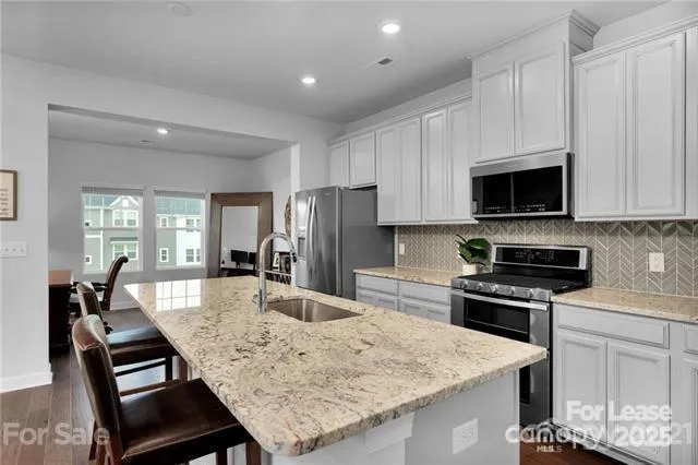 a kitchen with stainless steel appliances granite countertop a stove top oven a sink a dining table and chairs