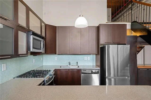 a kitchen with stainless steel appliances granite countertop a refrigerator a stove and a sink