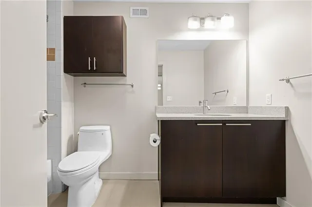 a bathroom with a granite countertop toilet sink and mirror