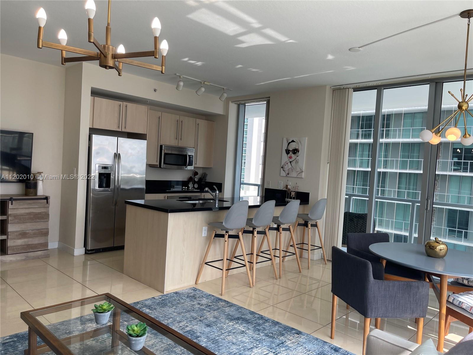 Brickell Miami, FL 33130 - Photo 8 of 30 a kitchen with stainless steel appliances granite countertop a stove a refrigerator a sink a dining table and chairs with wooden floor