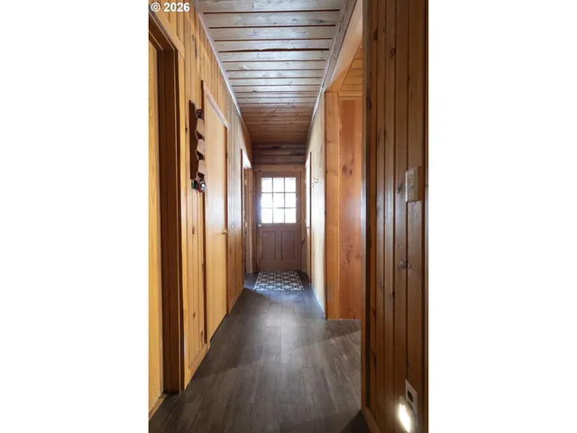 a view of a hallway with wooden floor and a bathroom