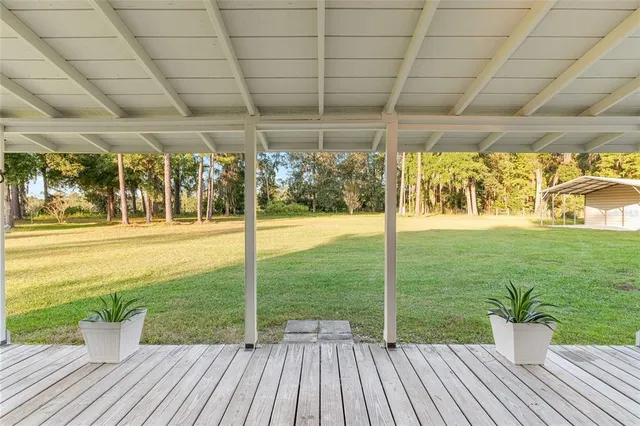 a view of a porch with a table and chairs next to a yard