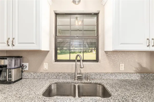 a large kitchen with granite countertop a sink stainless steel appliances and cabinets