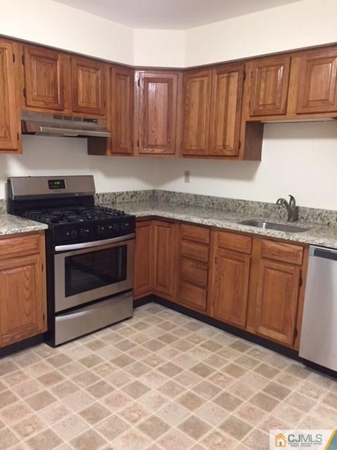 5001 Stonehedge Road, Unit 5001 Edison, NJ 08820 - Photo 1 of 13 a kitchen with granite countertop a stove top oven sink and cabinets