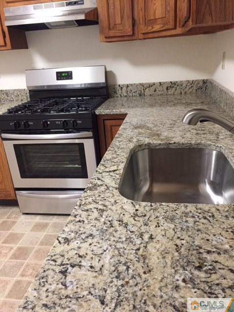 5001 Stonehedge Road, Unit 5001 Edison, NJ 08820 - Photo 2 of 13 a kitchen with granite countertop a stove and a sink
