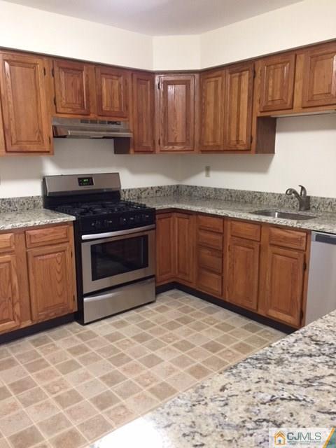 5001 Stonehedge Road, Unit 5001 Edison, NJ 08820 - Photo 3 of 13 a kitchen with granite countertop a sink stove and cabinets