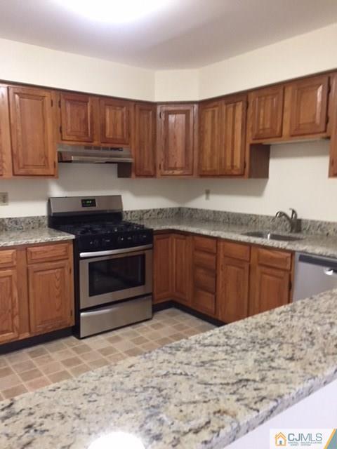 5001 Stonehedge Road, Unit 5001 Edison, NJ 08820 - Photo 4 of 13 a kitchen with granite countertop wooden cabinets and a stove top oven