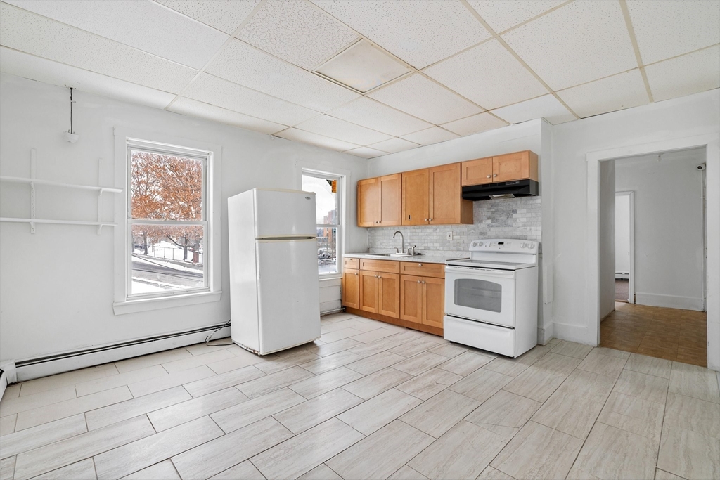 1 Ely Street Worcester, MA 01610 - Photo 7 of 25 a kitchen with a stove a refrigerator and white cabinets