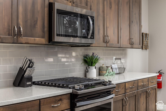 2600 Ocotillo Way, Unit 34 Santa Clara, UT 84765 - Photo 7 of 43 Kitchen featuring stainless steel appliances, decorative backsplash, light stone counters, and dark brown cabinets