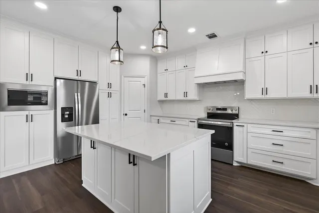 a kitchen with kitchen island white cabinets and stainless steel appliances